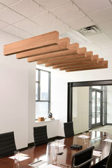 Multiple wooden acoustic beams with natural grain finish suspended from white drop ceiling in office conference room.