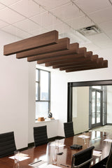 Multiple wood grain acoustic beams suspended horizontally across a drop ceiling in a conference room setting.