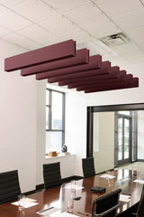 Burgundy felt acoustic beams suspended from drop ceiling in modern conference room above wooden table.