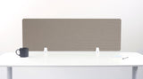 Beige desk divider with geometric line patterns, mounted on white desk with supporting brackets.