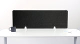 Black desk divider with geometric arc pattern, mounted on white desk with support feet.
