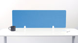 Blue desk divider with geometric line pattern mounted on white desk with black mug and notepad.