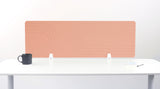 Terracotta desk divider with geometric line pattern mounted on white desk with black mug and white supports.