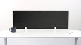 Black desk divider with geometric arc pattern, positioned on white desk with support legs.