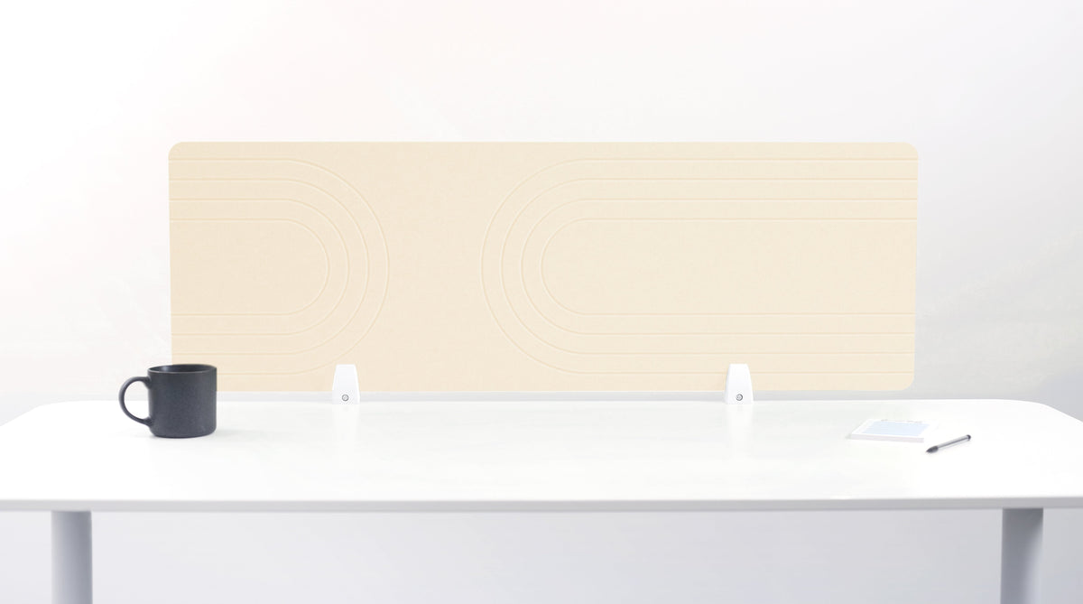 An ivory-colored felt desk divider placed on a white desk with a black mug and a pen beside it.