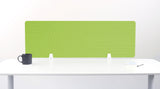 Green desk divider with geometric line pattern and white mounting brackets on white desk.