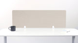 Beige desk divider with geometric arc pattern, mounted on white desk with black mug and office supplies.