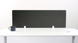 Dark gray desk divider with geometric line pattern, displayed upright on white desk with mug and papers.