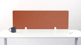 Terracotta desk divider with geometric arc pattern, standing on white desk with support brackets.