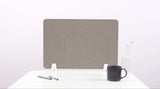 Gray desk divider with wave-shaped cutouts, positioned on white surface with white support feet.
