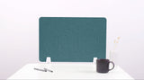 Teal desk divider with wavy cutout design, positioned upright on white desk surface with white mounting feet.