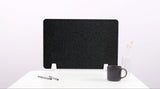 Black wave-shaped desk divider with rounded cutouts, standing on white desk with cup and office supplies.