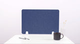 Blue desk divider with curved wave cutouts, positioned on white desk with coffee mug and office supplies.