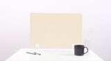 An ivory-colored felt desk divider placed on a desk with a pen and a coffee mug beside it, against a plain background.