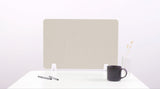 Beige desk divider with curved wave cutouts, mounted on white desk with pens, mug, and vase visible.