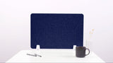 Navy blue desk divider with wavy cutout design mounted on white desk with office accessories.