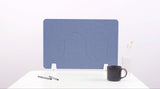 Blue wave-patterned desk divider with rounded cutouts, positioned on white desk with pens, mug, and vase.