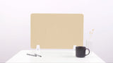 Beige desk divider with wavy cutouts, displayed on white desk with pens, mug, and vase.