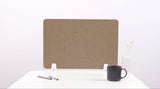 Tan desk divider with wavy cutout design, displayed on white desk with pens, dark mug, and vase.