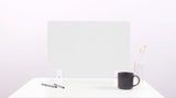 Frosted acrylic desk divider with wavy cutout design, positioned on white desk surface with pens, mug, and vase.