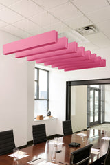 Pink felt acoustic beams suspended from white drop ceiling in conference room above wooden table.