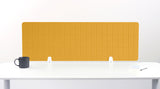 Yellow grid desk divider with white mounting brackets positioned on white desk surface next to dark mug and notepad.