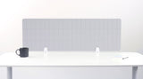 Light gray grid desk divider panel mounted on white desk with black mug and papers on surface.