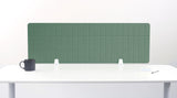 Green fabric desk divider with vertical ribbed pattern mounted on white desk with support brackets.