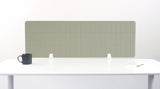 Green rectangular desk divider with vertical ribbed pattern mounted on white desk with metal supports.