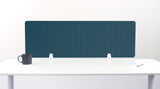 Teal grid desk divider with vertical panel segments mounted on white desk with support brackets.