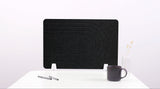 Black desk divider with curved geometric lines, white supports, positioned on white desk with mug and pens.