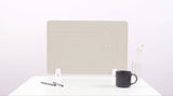 Beige desk divider with curved geometric lines, mounted on white stands behind desk with mug and pens.