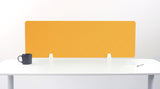 Yellow desk divider with diagonal quilted pattern mounted on white desk with black mug and notepad.