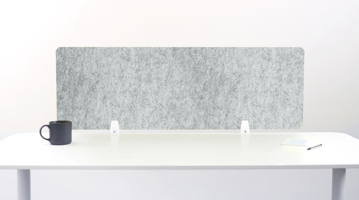 Gray acoustic panel on a white desk with a black mug