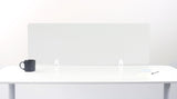 Frosted glass desk divider mounted on white brackets between desk sections with mug and papers visible.