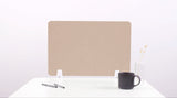 Beige desk divider with chevron pattern, two white mounting brackets, positioned on white desktop with coffee mug and pen hol