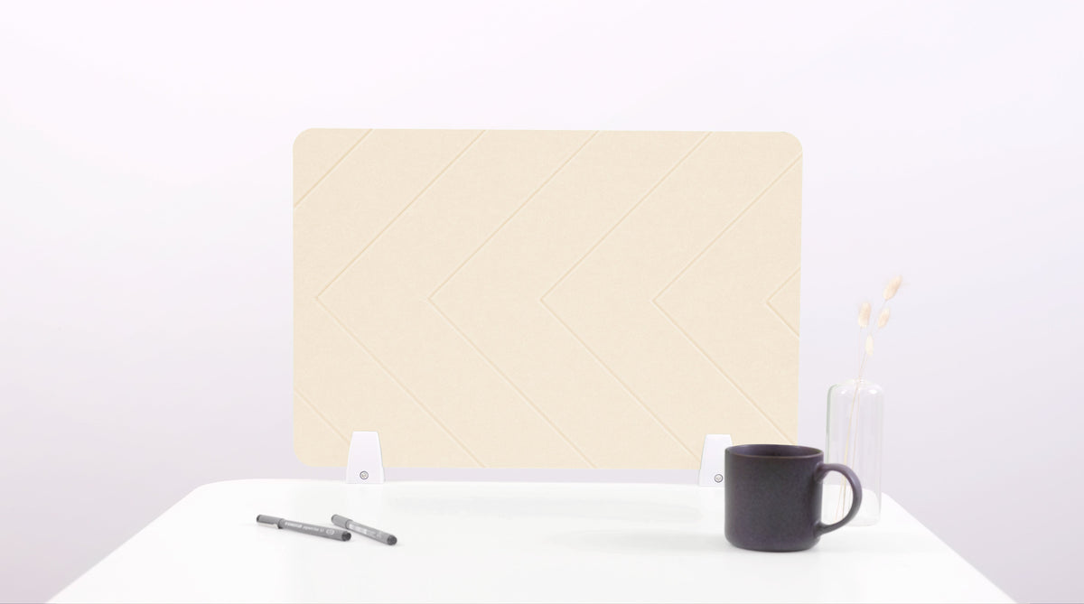 An ivory-colored felt desk divider placed on a desk with a pen and a coffee mug beside it, against a plain background.