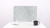 Felt screen protector on a white surface with a pen and mug