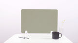 Sage green desk divider with chevron pattern standing on white desk beside pen holder, mug, and flower vase.