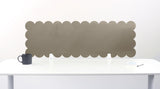 Scalloped headboard against a white wall with a table and mug in front.