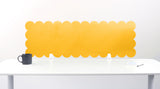 Yellow scalloped office partition on a white desk with a white background