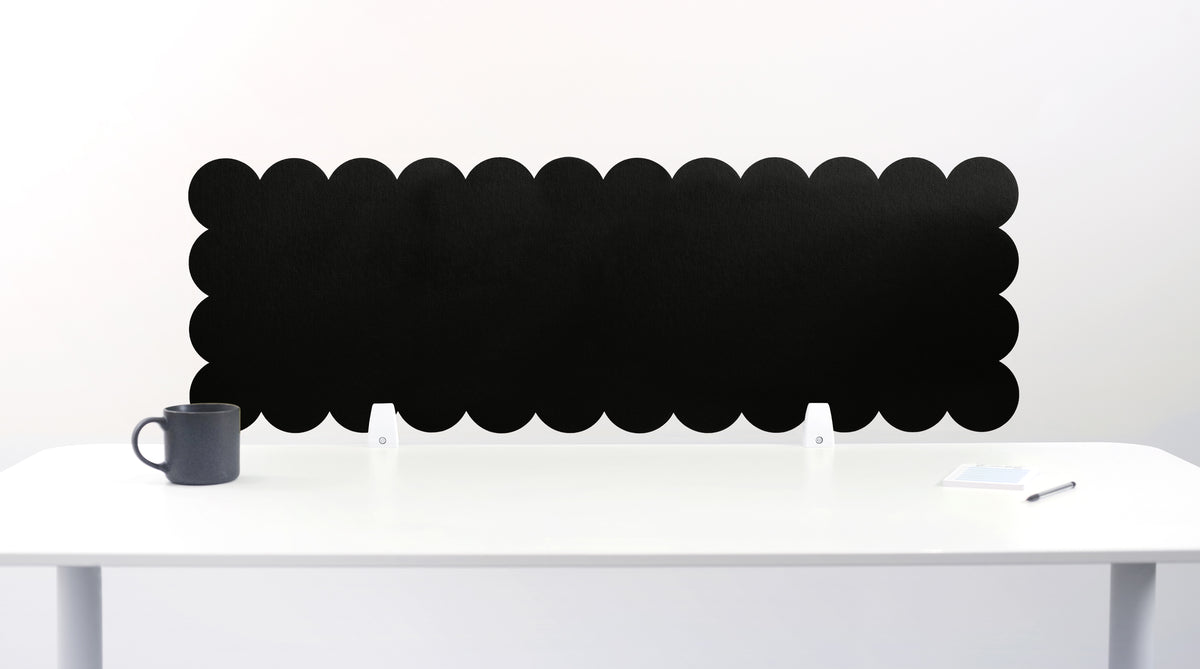 Scalloped black screen partition behind a white desk with a mug on a white background