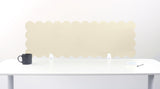 White scalloped headboard on a white wall with a black mug on a white surface.