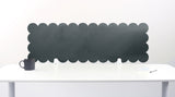 Scalloped black screen partition behind a white desk with a mug on a white background
