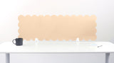 Beige scalloped headboard on a white wall with a white table and black mug in the foreground.