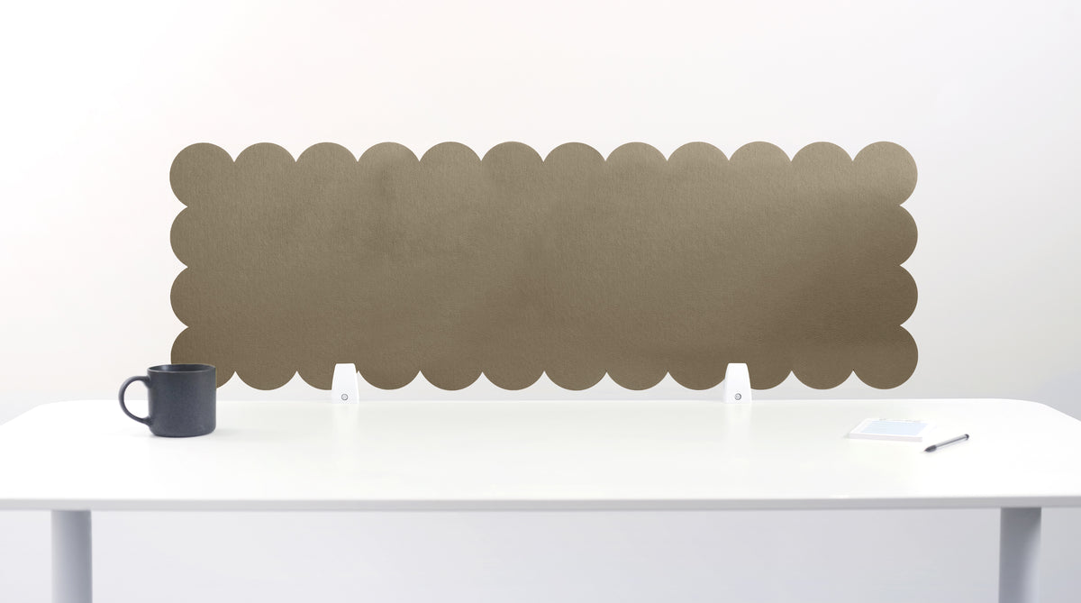 Scalloped headboard attached to a white wall above a white table with a black mug on it.