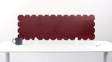 Red scalloped headboard against a white wall with a white desk and gray mug.