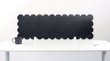 Scalloped black screen partition behind a white desk with a mug on a white background