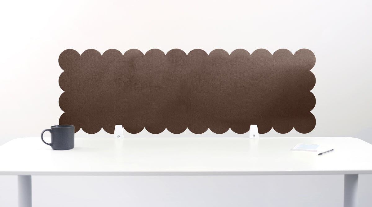 Red scalloped headboard against a white wall with a white desk and gray mug.