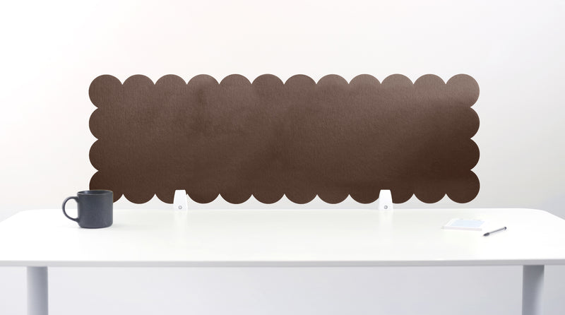 Red scalloped headboard against a white wall with a white desk and gray mug.